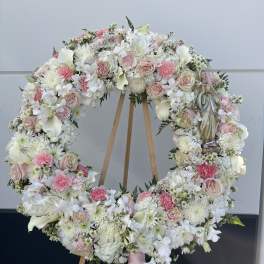 Large floral wreath on a wooden easel with pink and white flowers