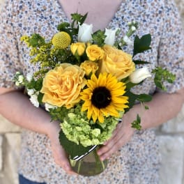 Yellow roses and a sunflower in a glass vase