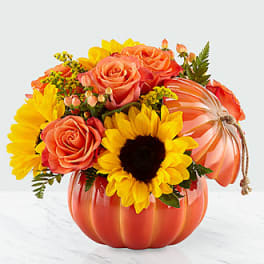Orange pumpkin vase with sunflowers and peach roses