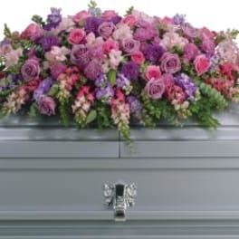 Large pink and purple floral casket spray on a gray casket