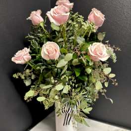 Pink roses in a white vase with airy greenery
