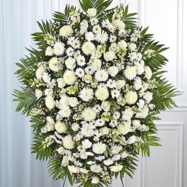 Large white funeral spray with daisies and roses on a stand