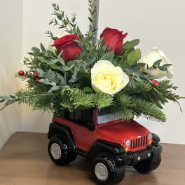 Red and white roses arranged in a red toy Jeep planter