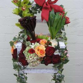 Floral chair arrangement with roses, orchids, calla lilies, and a red bow