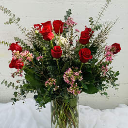 Red roses in a clear glass vase with pink filler flowers