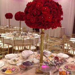 Large red rose centerpiece on a tall gold stand at a banquet table