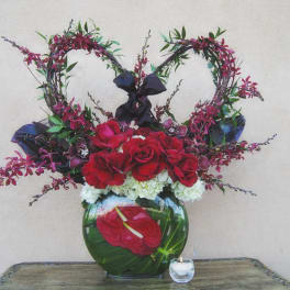 Heart-shaped floral arrangement with red roses in a glass vase
