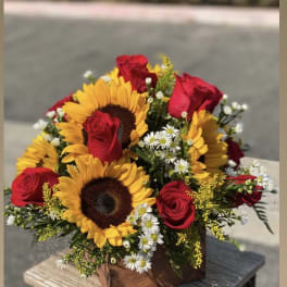 Bouquet of red roses and sunflowers in a wooden box