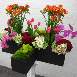 Colorful floral arrangement in black rectangular containers with orchids, roses, tulips, and hydrangeas