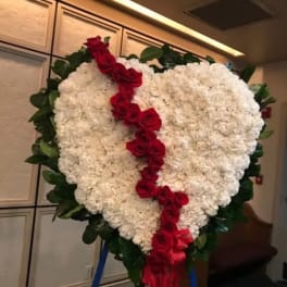 Heart-shaped white floral wreath with a red rose ribbon and green border