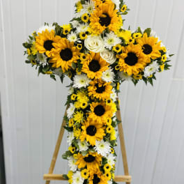 Cross-shaped floral spray with sunflowers and white daisies on an easel