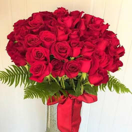 Bouquet of red roses in a tall vase with a red ribbon