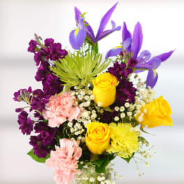 Colorful bouquet of purple, yellow, and pink flowers in a glass vase