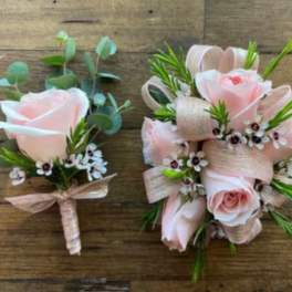 Two pale pink rose boutonnieres with ribbon and small white flowers