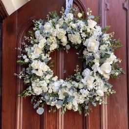 White floral wreath with roses on a wooden door