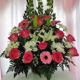 Pink roses, lilies, and daisies arranged in a tall bouquet