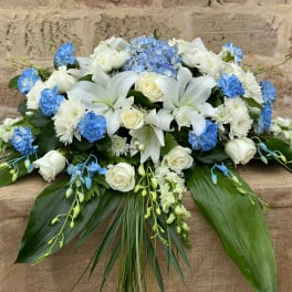 White lilies and roses with blue flowers in a low arrangement