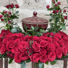 Heart-shaped arrangement of red roses with a decorative lidded box behind it