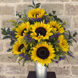 Sunflower arrangement in a silver vase with purple accents