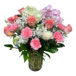 Pink roses and carnations in a glass vase with white and lavender blooms