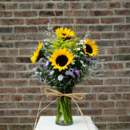 Sunflower bouquet in a clear glass vase with a raffia bow