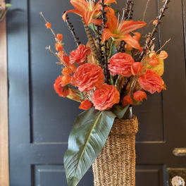 Orange floral arrangement in a tall woven vase