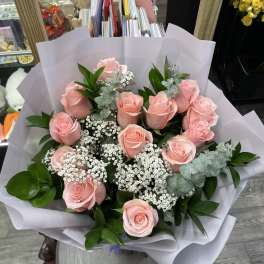 Bouquet of pink roses with white filler flowers wrapped in white paper