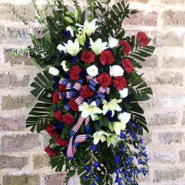 Standing floral spray with red, white, and blue flowers and ribbon