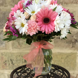 Bouquet of pink and white daisies in a glass vase with a pink ribbon