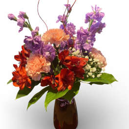 Bouquet of purple and orange flowers in a brown vase