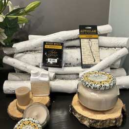 Candles and fragrance products arranged on wood slices with white branches