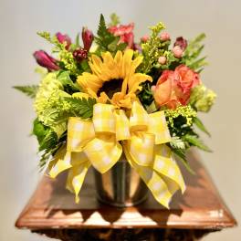 Sunflower bouquet with pink roses in a vase and yellow ribbon