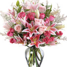 Pink lilies and roses arranged in a clear glass vase