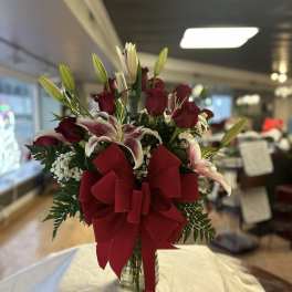Red roses and lilies in a glass vase with a large red bow