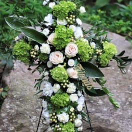 Cross-shaped floral funeral spray with white and green flowers