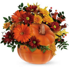 Fall bouquet in a pumpkin-shaped container with orange and red flowers