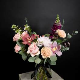 Mixed bouquet in a glass vase with pink, yellow, orange, and white flowers