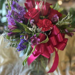 Bouquet of red roses and purple flowers with a pink ribbon