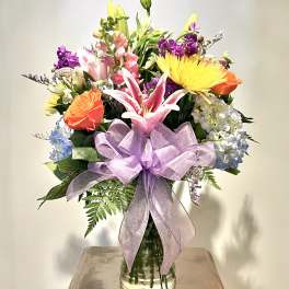 Mixed bouquet in a glass vase with a lavender ribbon