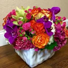 Colorful bouquet of roses, calla lilies, and orchids in a white vase