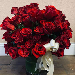 Bouquet of red roses in a glass vase with a white ribbon