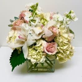Pink roses and white lilies arranged in a square glass vase