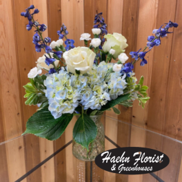 White roses and blue hydrangeas in a glass vase