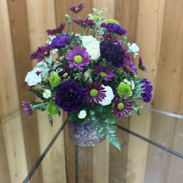 Purple and white flower arrangement in a glittery vase