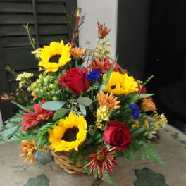 Basket arrangement with sunflowers, red roses, and mixed flowers