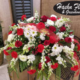 Red and white floral arrangement with roses and daisies in a basket