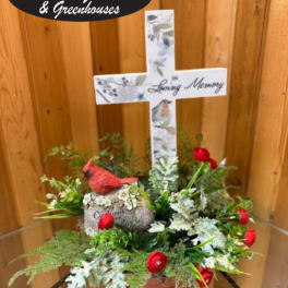 Memorial cross arrangement with red flowers and a bird figurine
