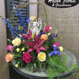 Colorful floral arrangement with roses, lilies, and an angel figurine
