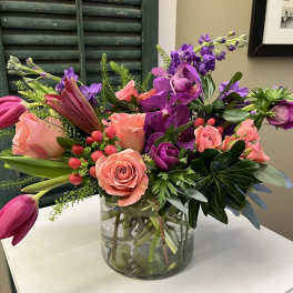 Mixed bouquet of pink and purple flowers in a clear glass vase
