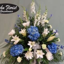 Blue hydrangeas and white lilies in a tall floral arrangement